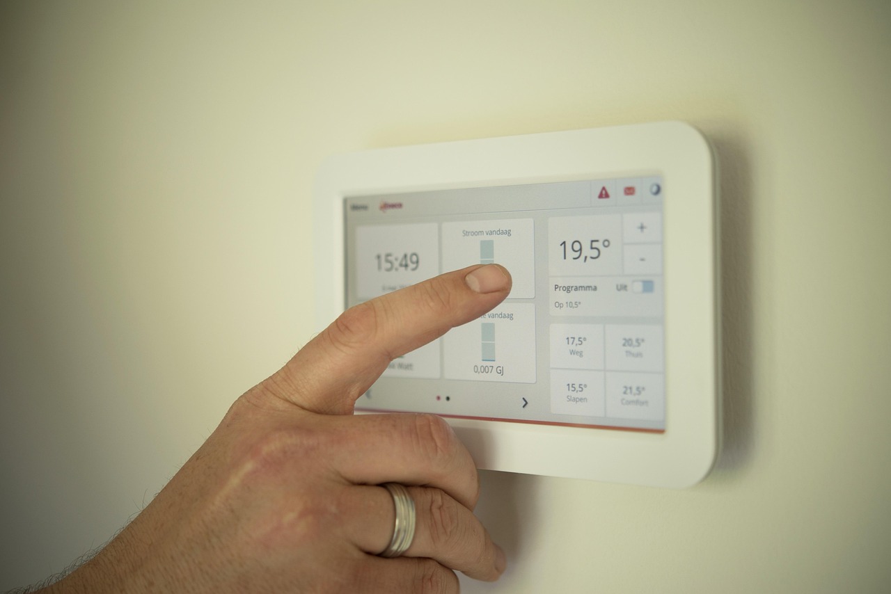 A hand adjusting a wall thermostat in a home.