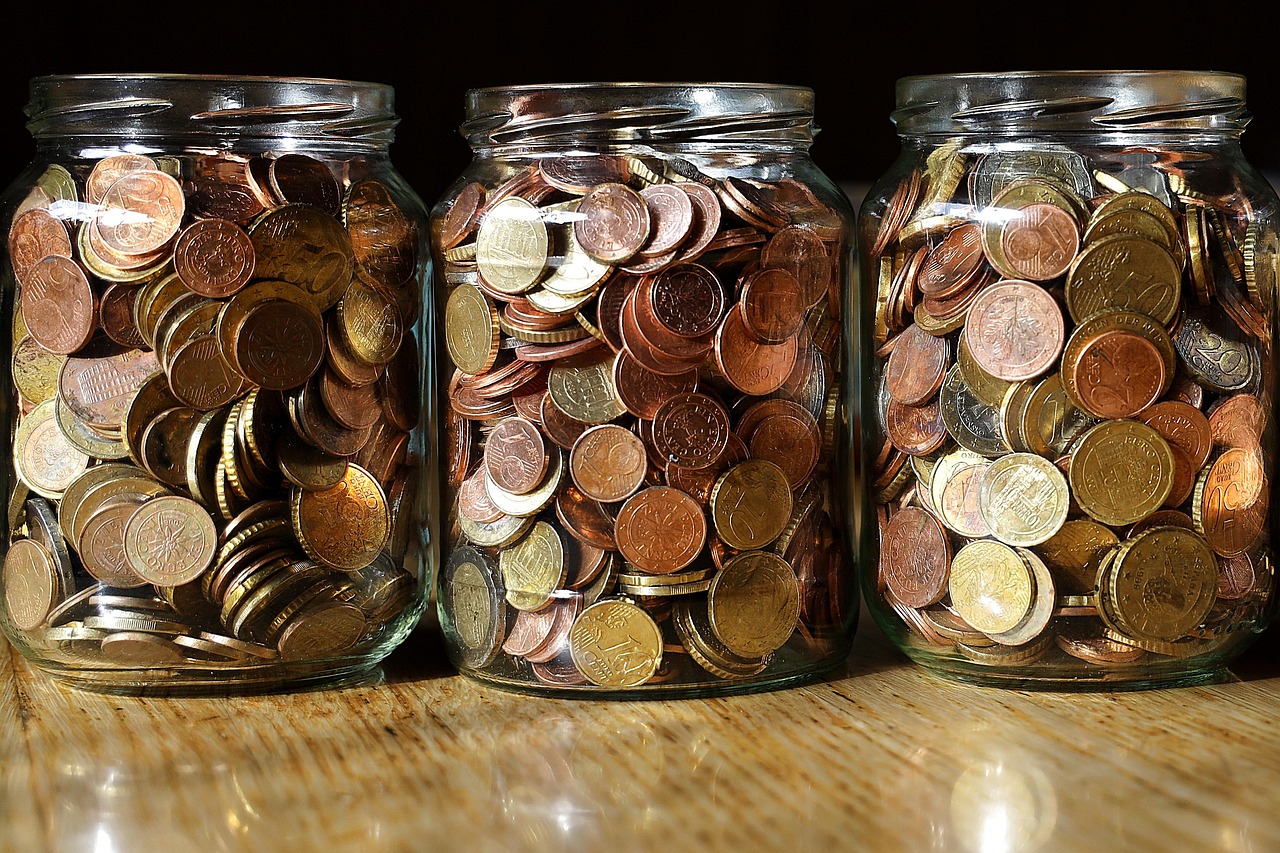 A glass jar of coins labeled for retirement savings.