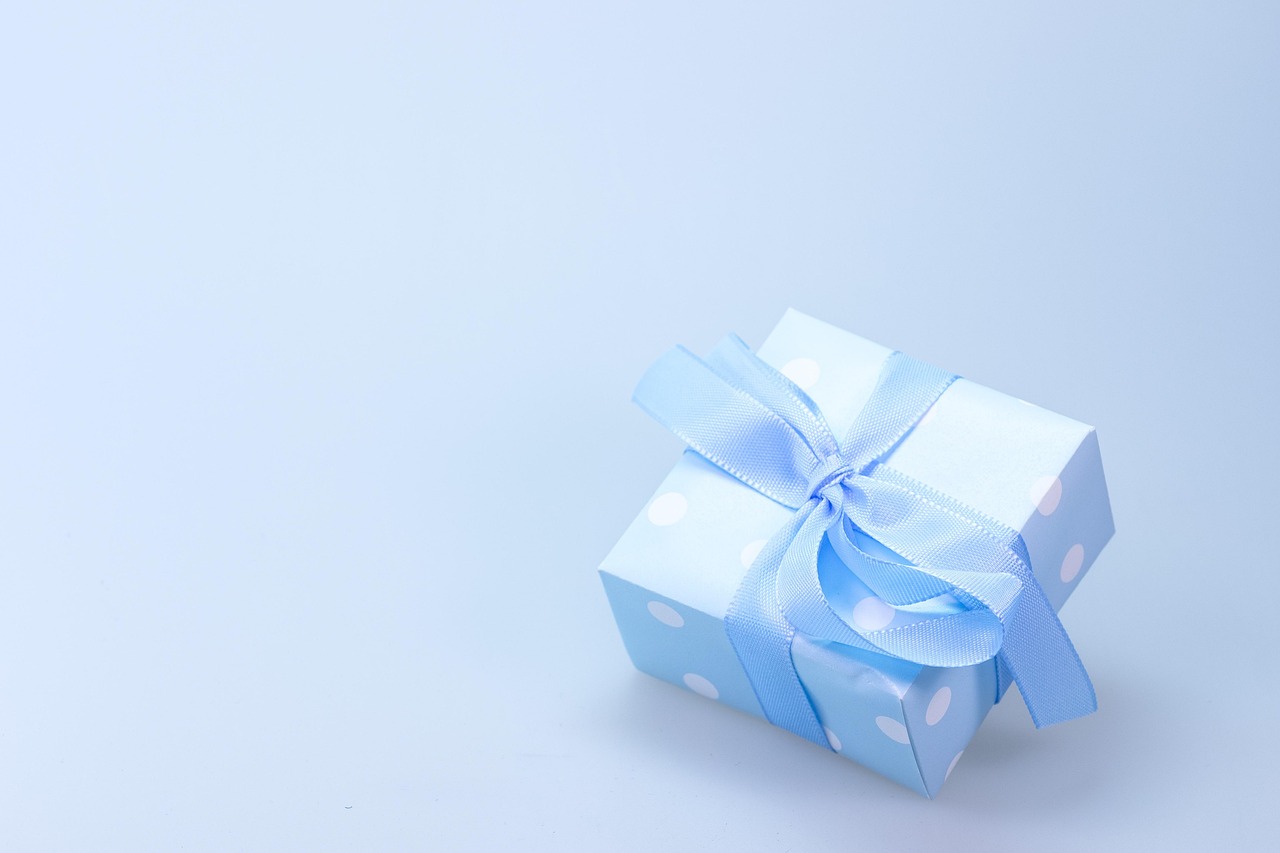 A pile of wrapped holiday gifts on a wooden floor.