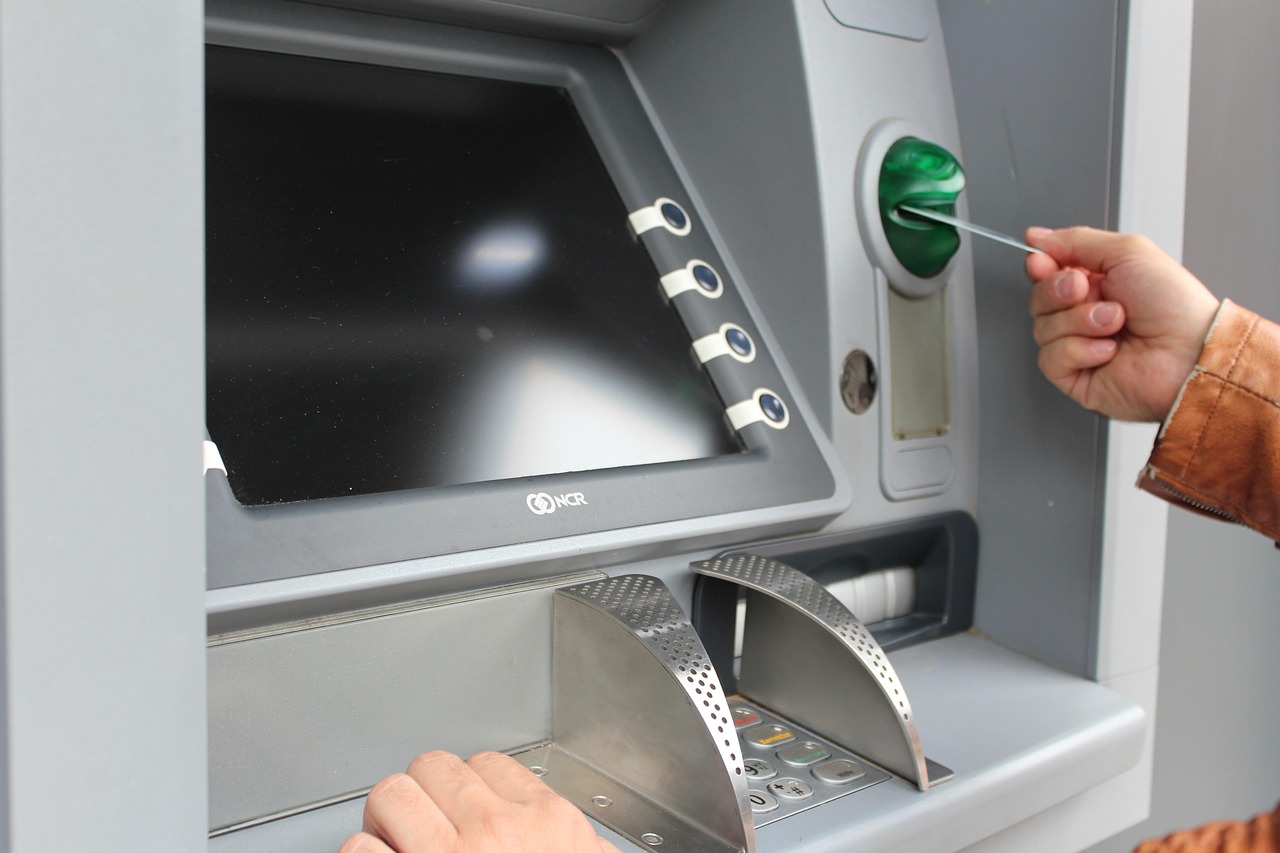 A hand taking cash from an ATM.