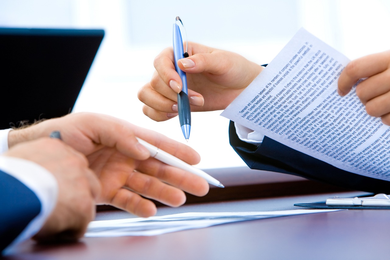 A stack of household bills and a pen on a desk.
