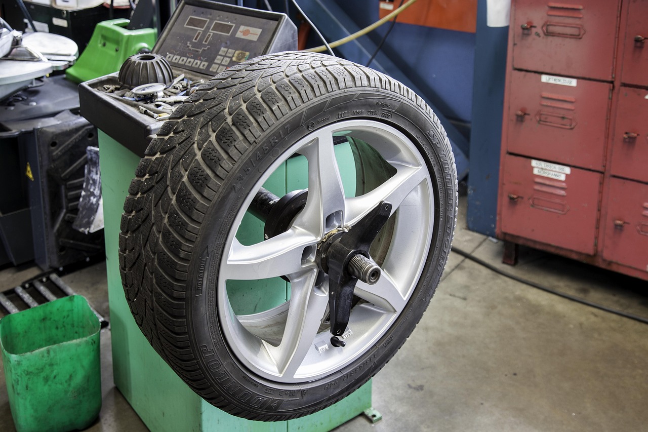 A mechanic replacing a tire on a car in a service bay.