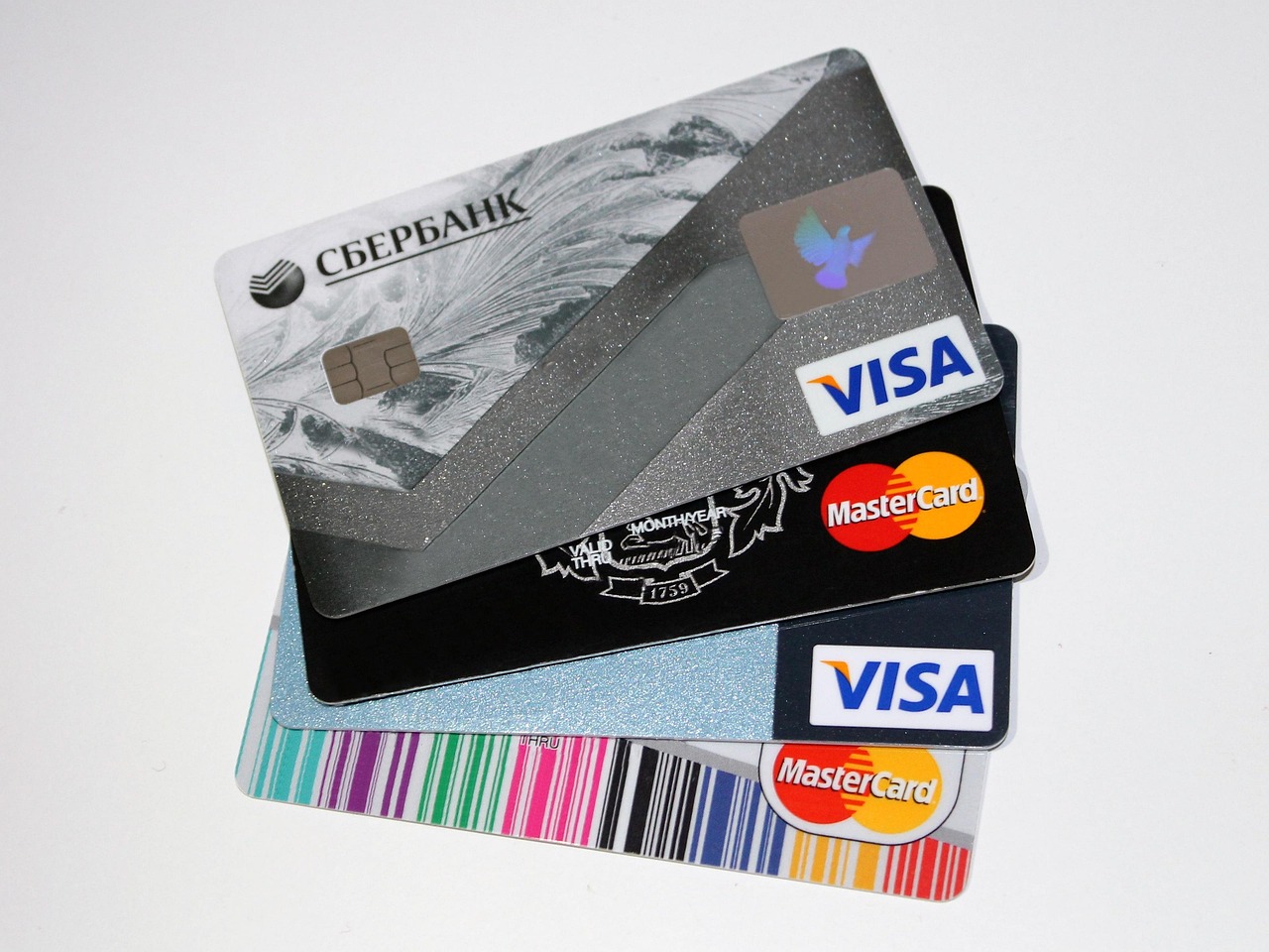 A small stack of credit cards next to a pen and a payment statement.