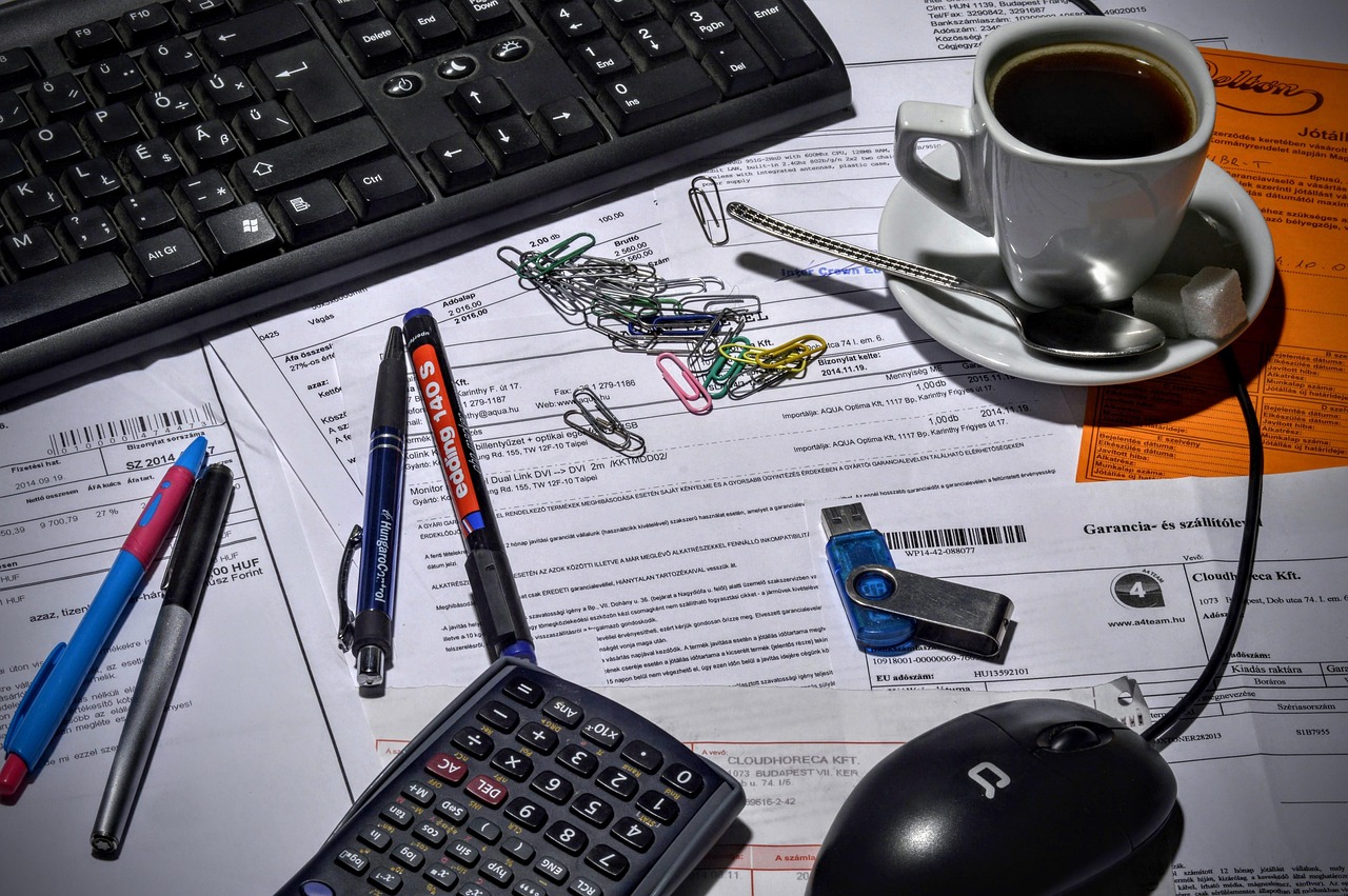 A calculator resting on a pile of receipts on a wooden desk.